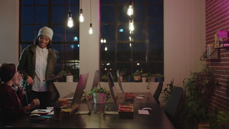 business-people-working-late-african-american-team-leader-woman-using-digital-tablet-computer-discussing-project-pointing-at-screen-colleagues-sharing-ideas-in-office-at-night