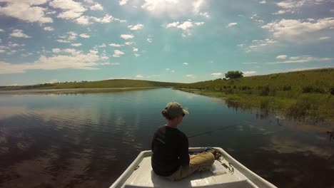 girl sitting on the front of a boat fishing for bass on a clear lake on a sunny day