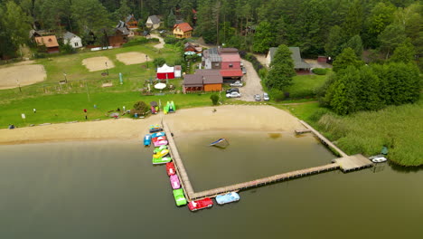 toma aérea de un lago natural con playa de arena, campo de voleibol y costa en un paisaje verde - hartowiec, polonia
