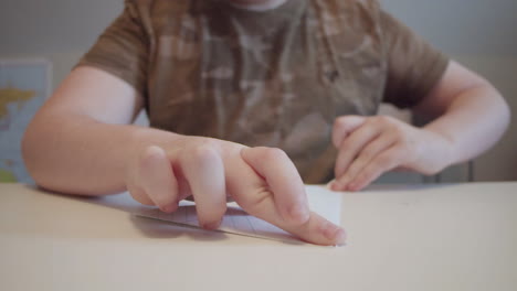 young boy folding a paper airplane