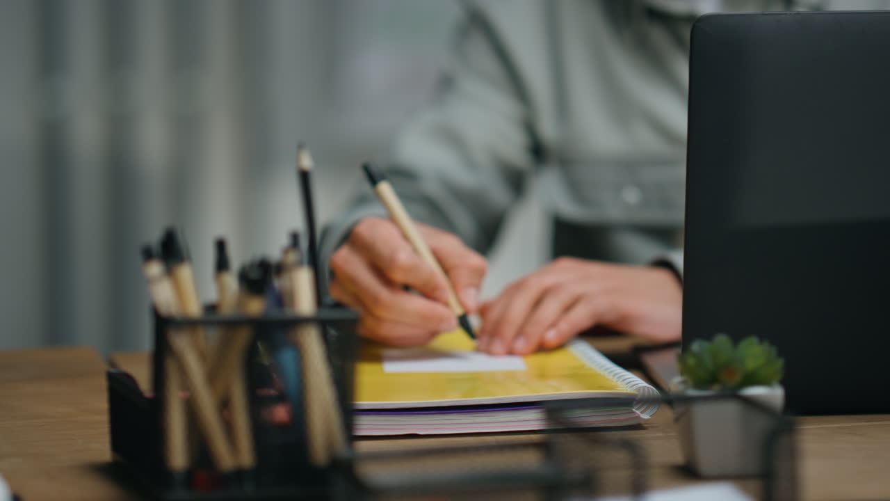 Manager sorridente che scrive un appunto su un piccolo foglio alla scrivania, primo piano. Ragazzo che lancia.