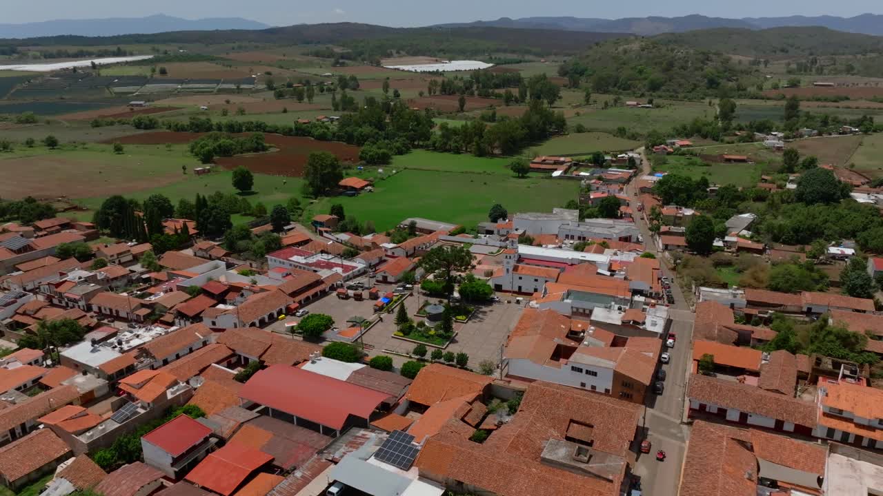 Scenic aerial view captures the rustic charm of Chiquilistlan, Jalisco, Mexico under a clear blue sky, showcasing vibrant terracotta roofs and lush surrounding countryside
