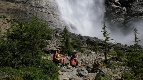 front view of young caucasian hiker couple with backpack sitting and relaxing in the forest 4k