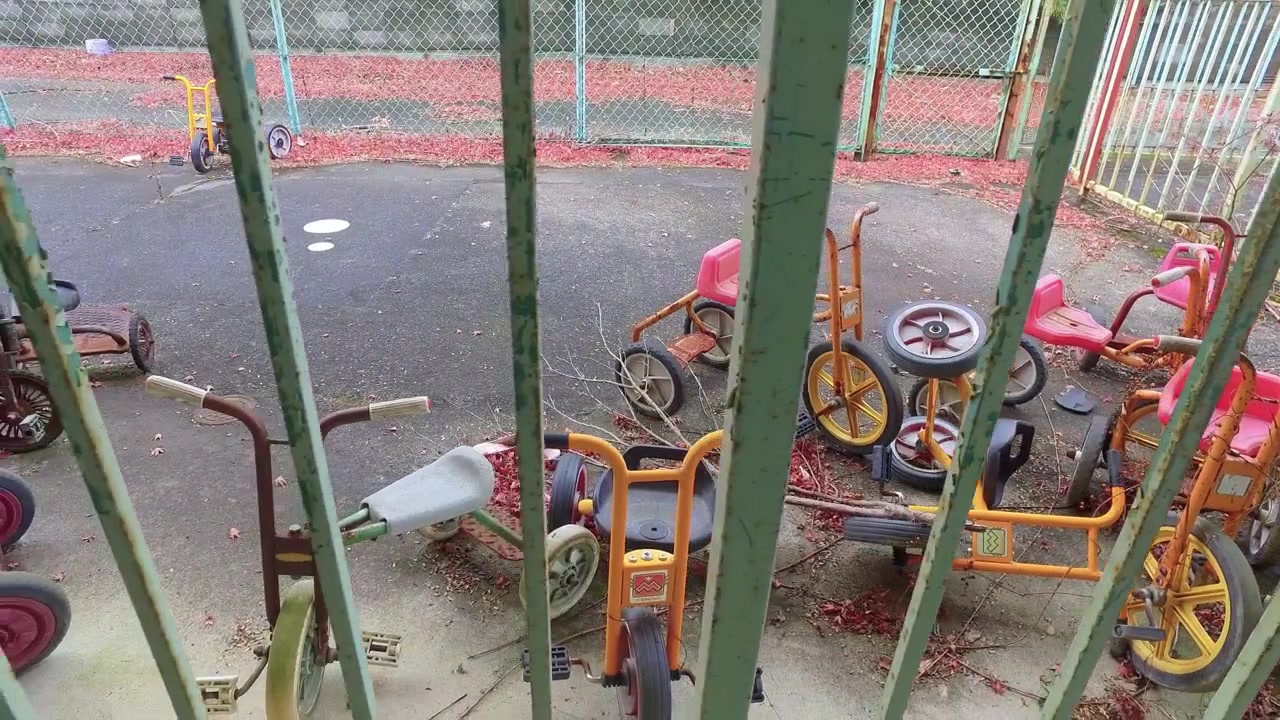 POV sinistro olhando através de barras de metal para brinquedos de infância em decomposição