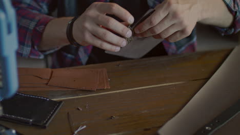 craftsman making leather key chain in home workshop. leather workshop