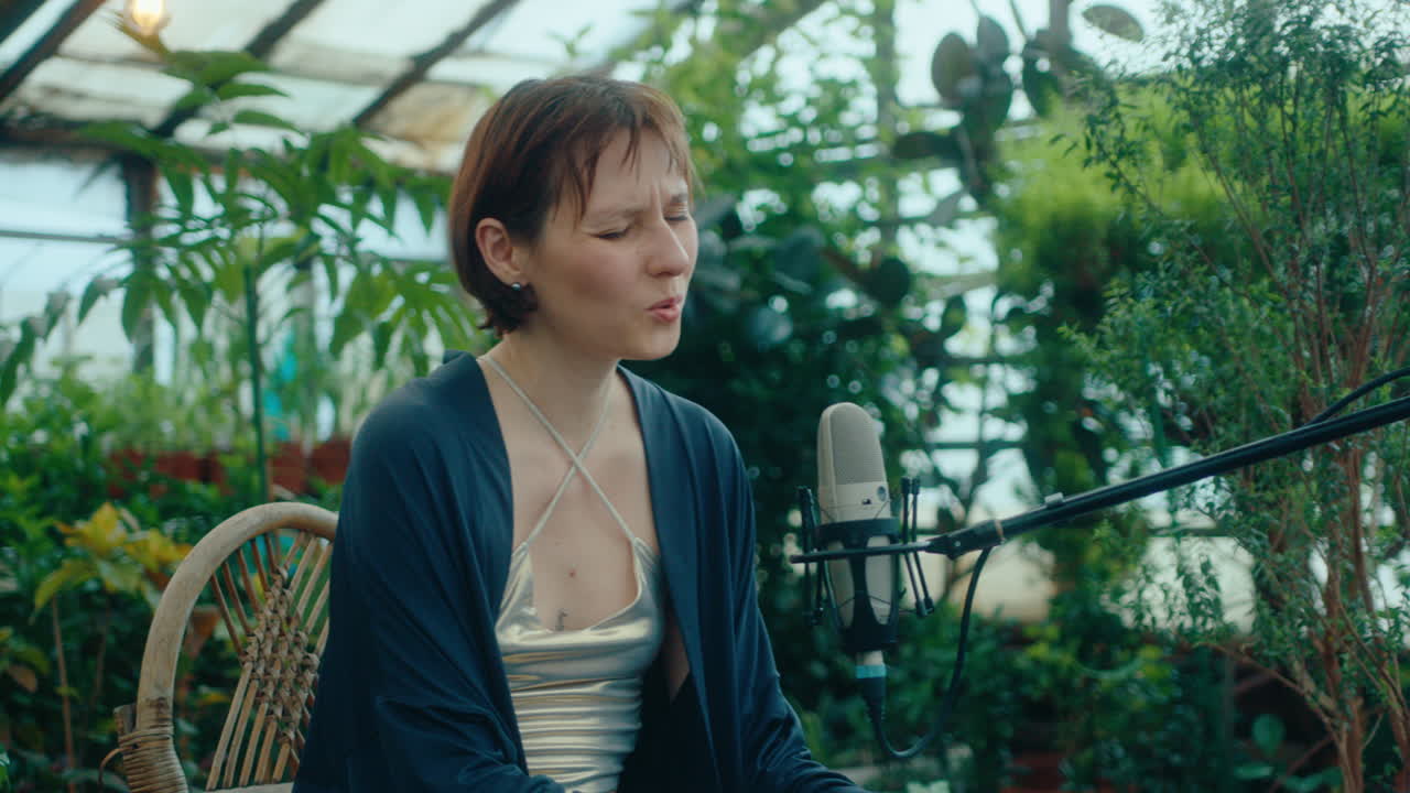 Female Musician Playing Keyboard and Singing during Performance in Greenhouse