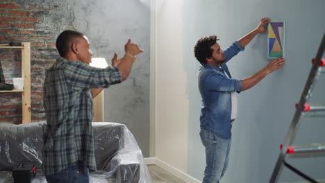 black guy advises brother to turn abstract picture on wall