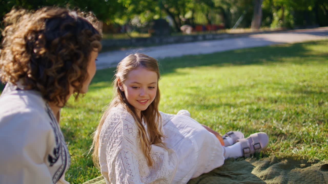 Small girl sitting picnic resting summer lawn closeup. Mother daughter relaxing