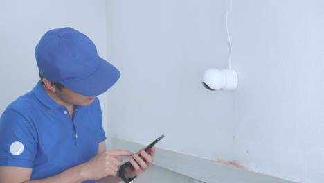 hombre asiático técnico trabajador uso de teléfono móvil control de seguridad cámara de cctv