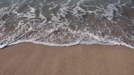 small waves lapping against sandy beach, sun glistening on surface on sunny day, waikiki, hawaii