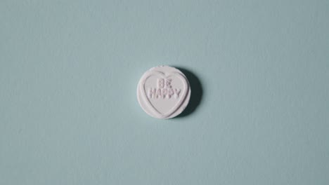 파란색 배경에 행복 메시지와 함께 심장 사탕을 손에 들고