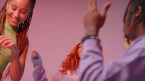 studio shot of young gen z friends dancing at club against pink background 10