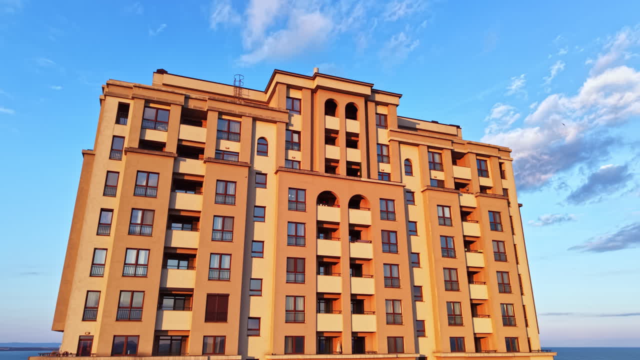 Edifício imponente contra o céu azul com nuvens ao fundo, perto do oceano, durante o entardecer em uma área costeira.