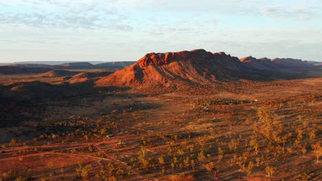 distant view of the rocky mountain amidst the red sand dunes in alice springs town, australia