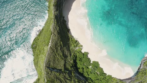 Aerial-shot-of-Nusa-Penida's-iconic-coastline-in-Bali,-with-the-emblematic-Kelingking-Beach-from-above,-with-turquoise-waters,-dramatic-cliffs,-and-pristine-sandy-shores-creating-a-breathtaking-scene