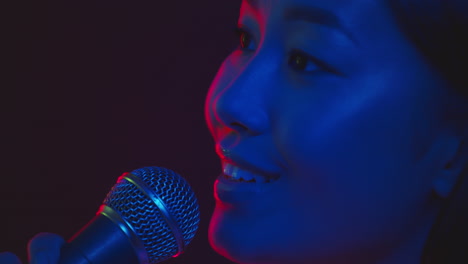 woman singing into microphone in neon light