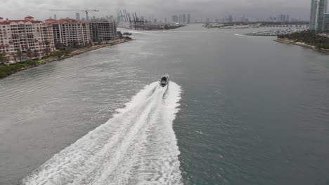 Vista-Aérea-Del-Barco-Conduciendo-A-Través-Del-Océano-En-El-Horizonte-De-La-Ciudad