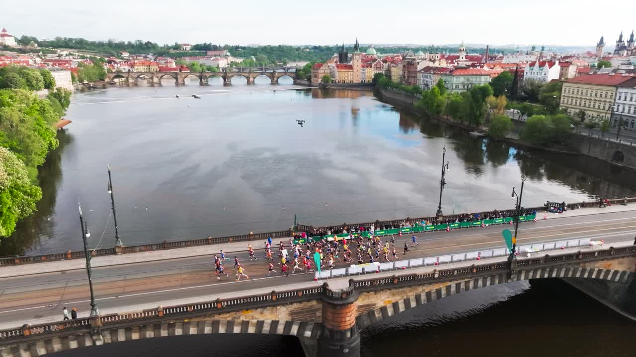 Grande gruppo di corridori attraversa un ponte sul fiume Moldava, Repubblica Ceca.