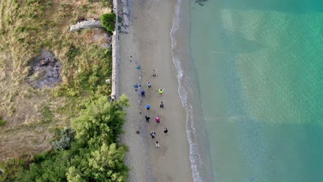 Vista-Aérea-De-Un-Grupo-De-Personas-Haciendo-Yoga-En-La-Playa