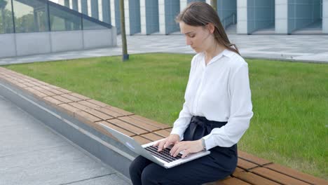 focused corporate woman typing on laptop outdoors