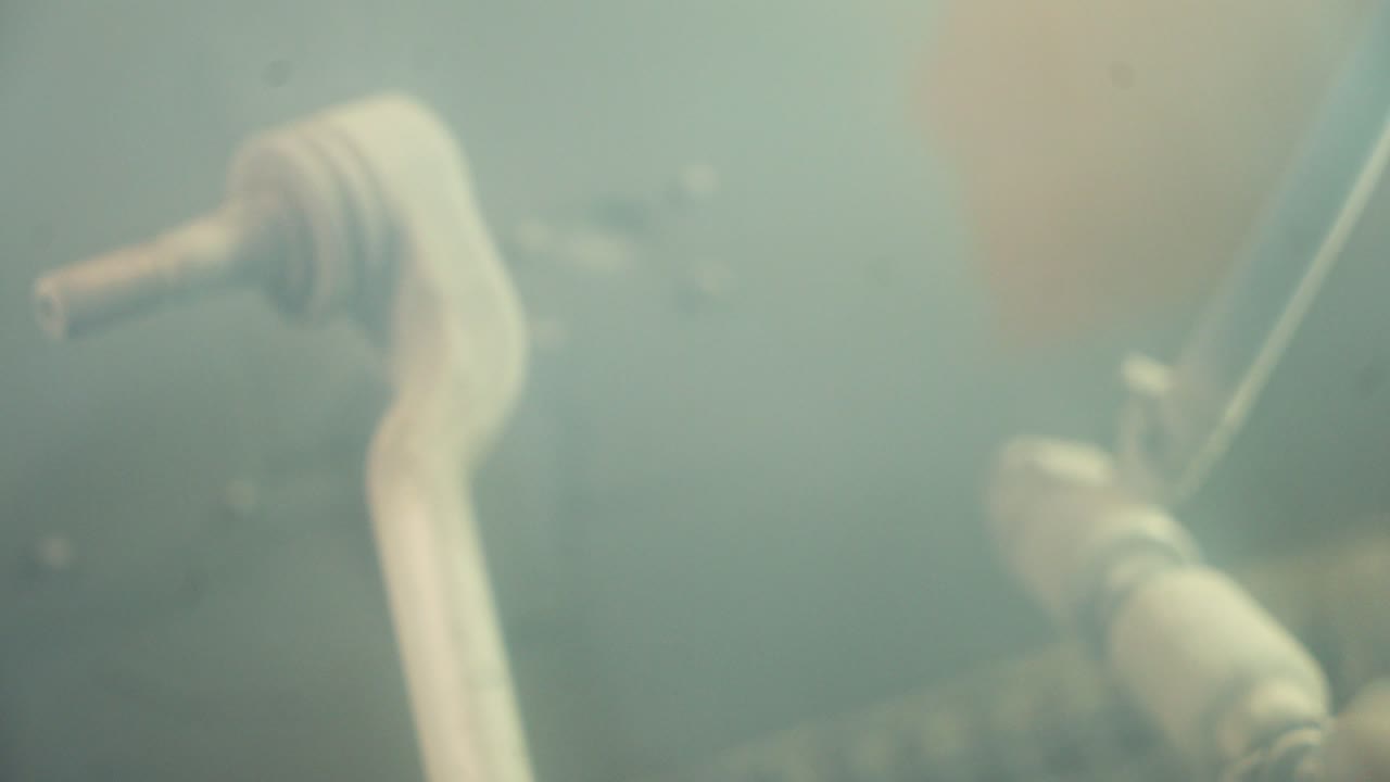 Details from factory for production. Construction worker painting mechanical details with spray gun