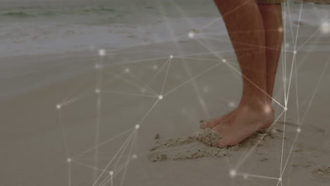 network of connections against low section of a man standing at the beach