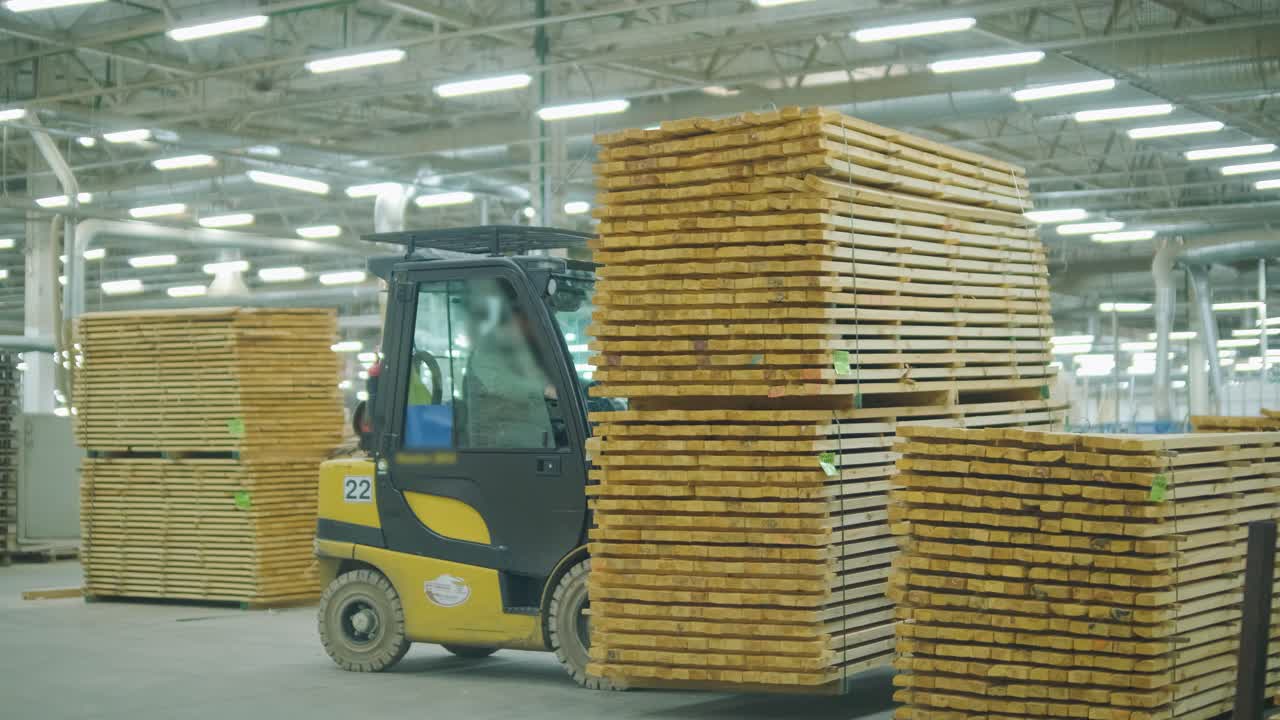 Forklift operator moving stacked wooden planks in a timber factory