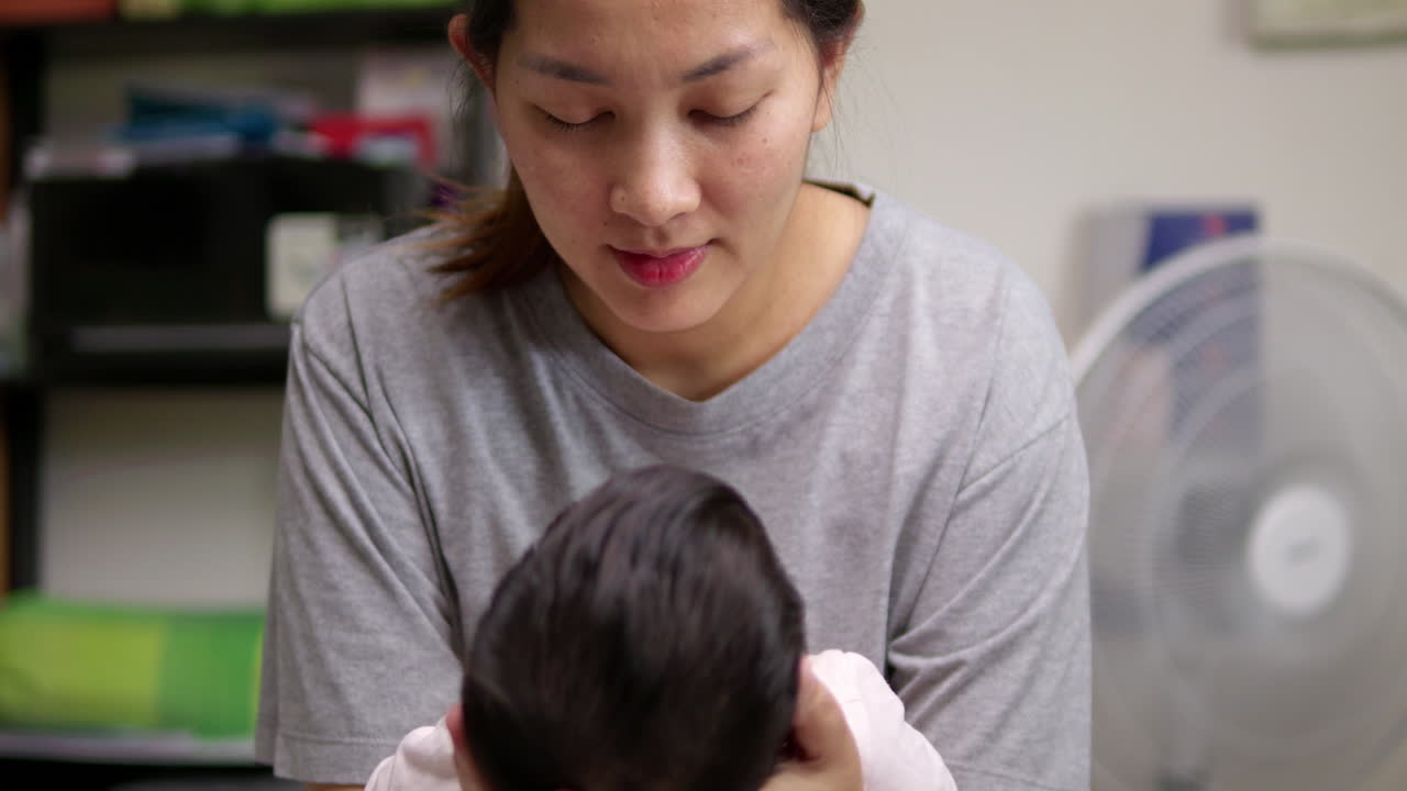 갓 태어난 아기를 품에 안고 자신을 바라보게 하며 아이를 내려다보며 미소 짓는 모습.