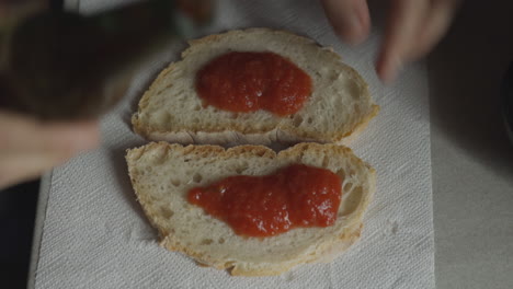 caucasian hands prepare pizza for snack, on bread's slices, with tomato sauce and mozzarella cheese