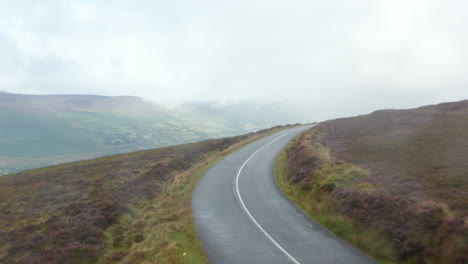 Coches-Circulando-Por-La-Carretera-Que-Conduce-A-Través-De-Páramos-En-Las-Montañas.-Clima-Lluvioso-Con-Nubes-Bajas-En-El-Valle.-Irlanda