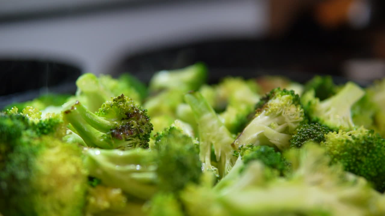Fresh steamed broccoli smoking in the skillet or wok - slow pull back close up