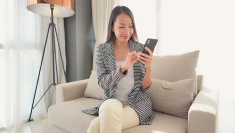 a young asian woman interacts with her smartphone.
