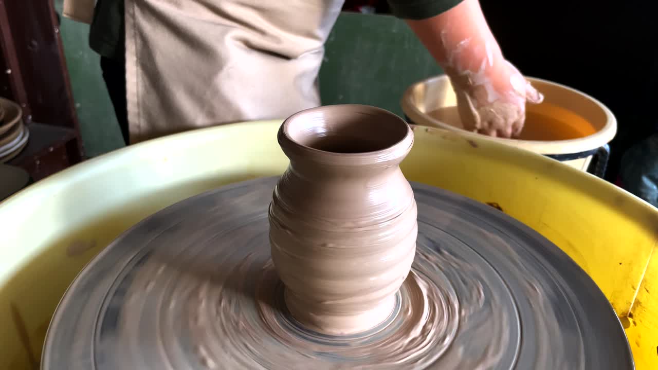 아이의 손은 도자기 바에 점토 용을 조각합니다.