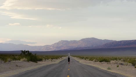 Mujer-Caminando-En-Medio-De-La-Carretera-En-El-Parque-Nacional-Del-Valle-De-La-Muerte-En-California,-Estados-Unidos