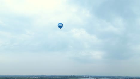 looking up at blue hot air balloon flying across hendrik-ido-ambacht under clouds