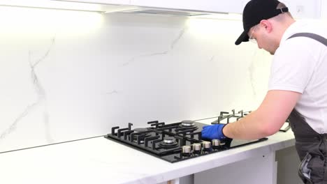 a man install a burner on a gas stove in the kitchen the master repairs the gas panel