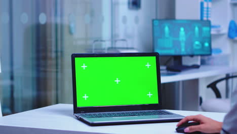 médico que utiliza una computadora portátil con pantalla verde