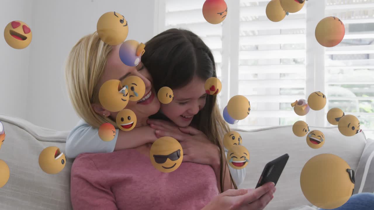 animación de iconos emoji sobre madre y hija caucásicas usando un teléfono inteligente