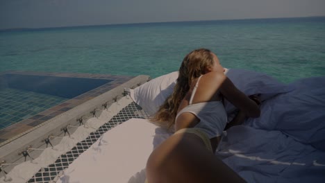 young woman on vacation relaxes in her overwater bungalow. luxury vacation concept