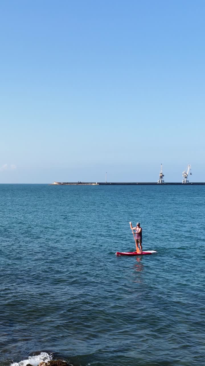 Man paddle boarding in the calm ocean. Vertical