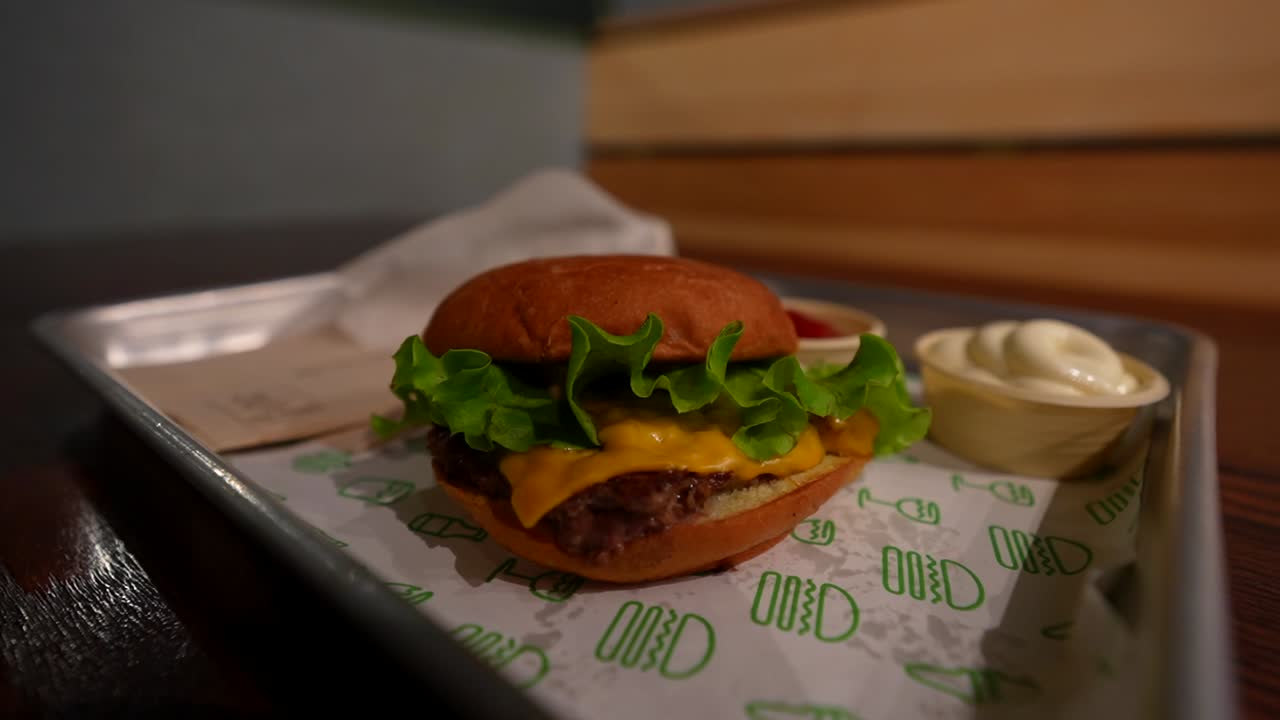 Shake Shack burger with cheese, lettuce, mayo, and ketchup on a tray in a London restaurant