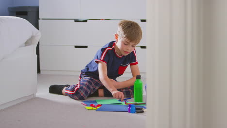 boy in bedroom making card to celebrate birthday or mothers day