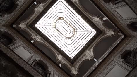 Looking-up-rotating-shot-looking-up-towards-glass-window-ceiling-with-symmetrical-architecture