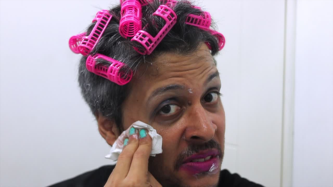 Man with Hair Rollers and Messy Makeup Applying Lipstick