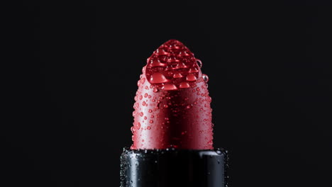 primer plano de un lápiz labial rojo con gotas de agua