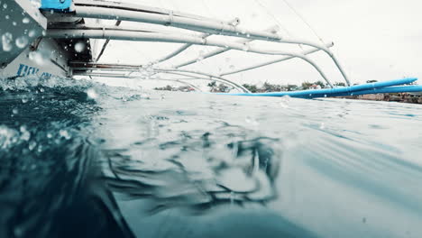 Cinematic-slow-motion-shot-of-an-outrigger-boat-from-the-front-looking-back-close-to-the-waterline-in-the-Philippines,-Asia,-Slomo