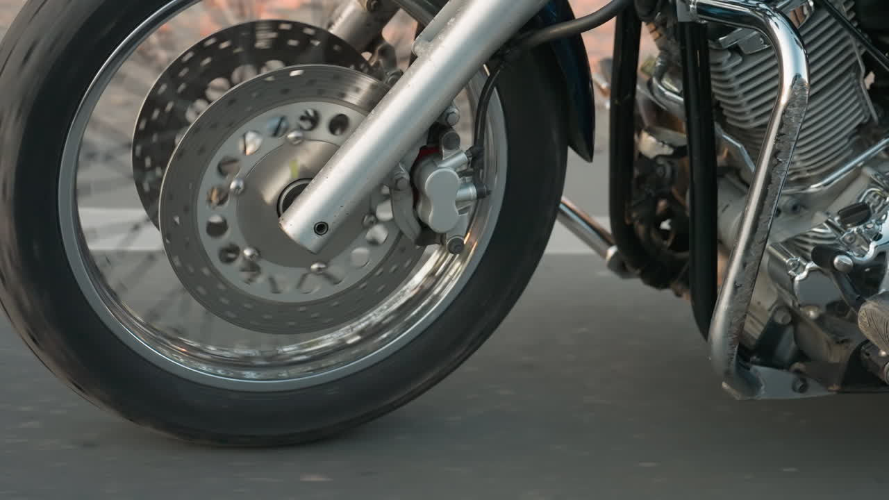 Leg view of rider and passenger on motorcycle footrests while traveling on asphalt road, showcasing leather boots, chrome engine details, and motion blur that conveys speed