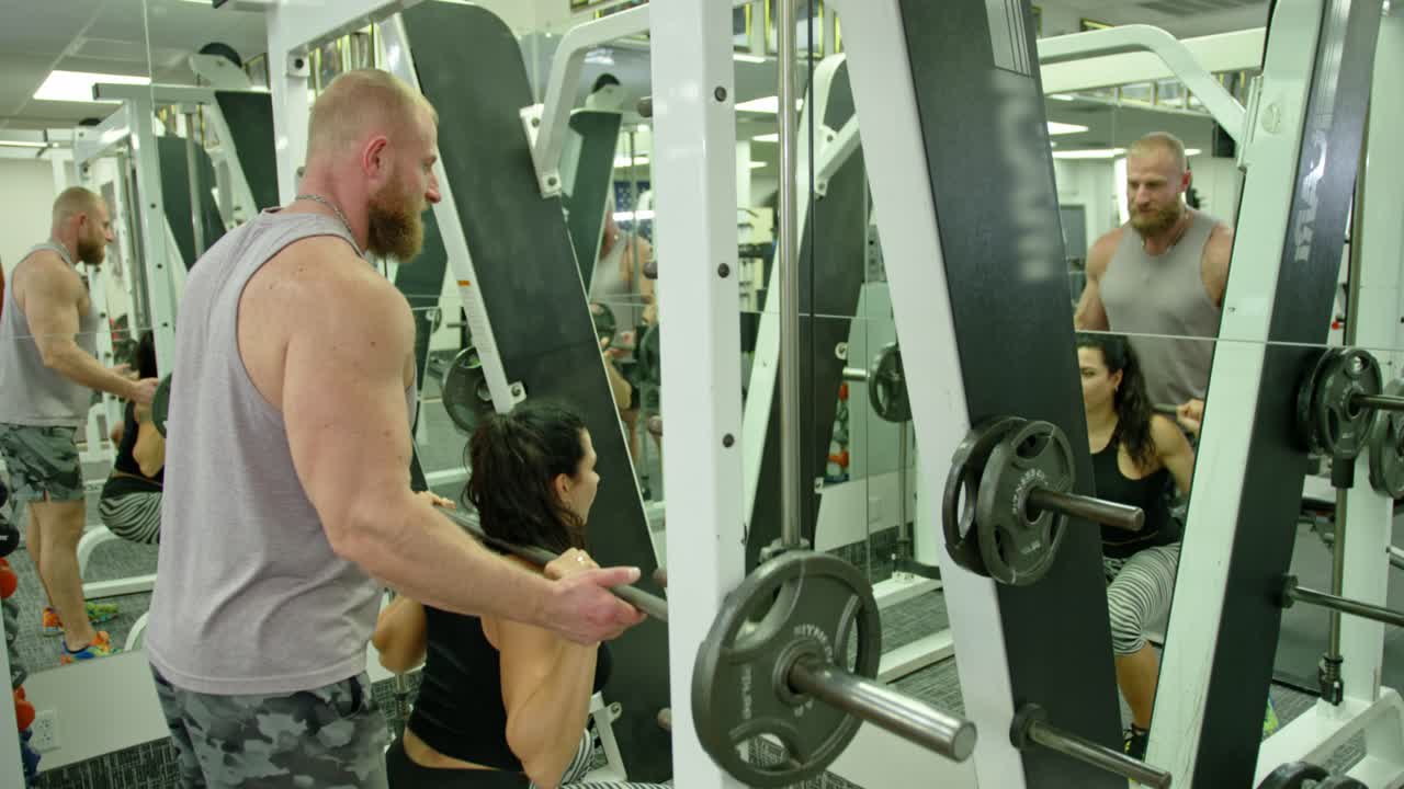 Fit young woman during sports training with coach in modern gym