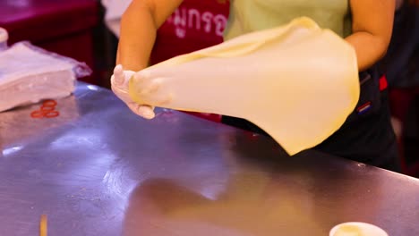 vendor prepares roti dough at bangkok market