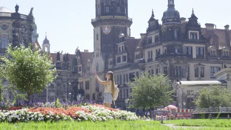 Woman Walking in City Park with Large Building Grass and Plantlined Facade